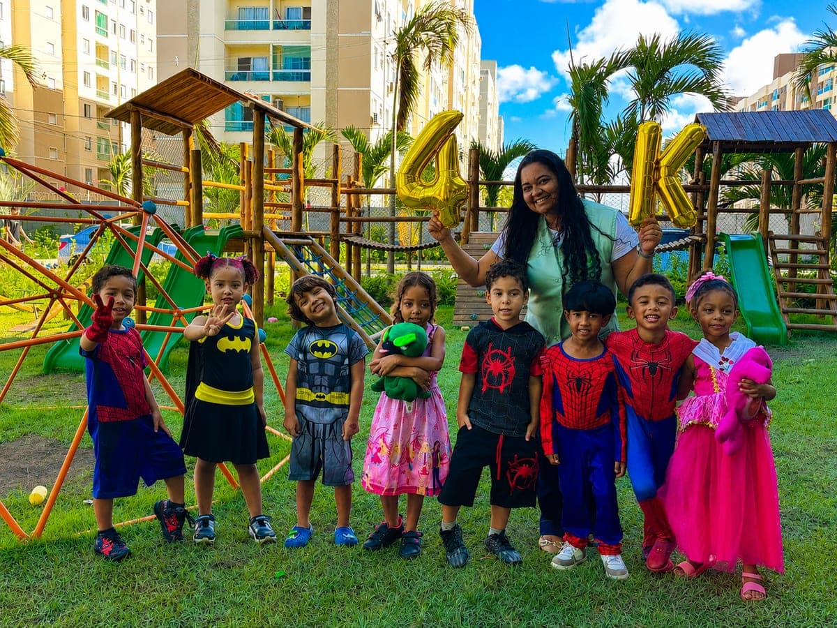 Turma da Educação Infantil do COC fantasiada no parquinho, ao lado da professora
