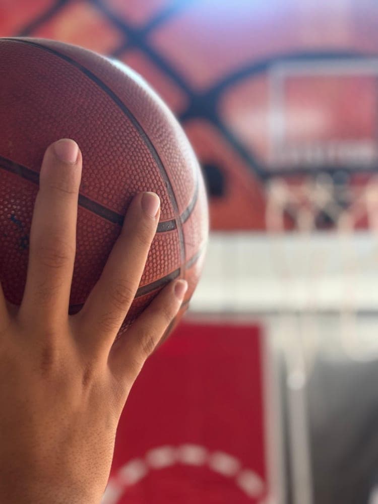 Aluno do Colégio COC segurando uma bola de basquete na quadra